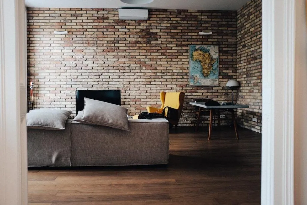 photo of HVAC for 1,000 sq ft home mounted to brick wall above a couch in living room