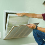 Professional repair service man or DIY homeowner removing a dirty air filter so he can replace it with a new clean one.