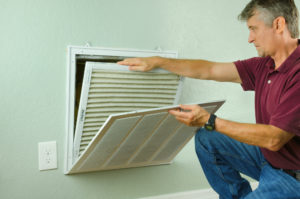 Professional repair service man or DIY homeowner removing a dirty air filter so he can replace it with a new clean one.