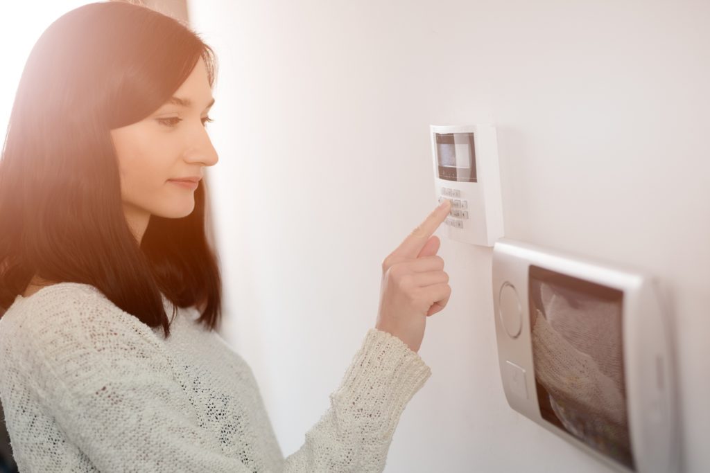 Woman improving HVAC efficiency by programming thermostat