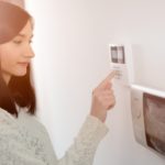 Woman improving HVAC efficiency by programming thermostat