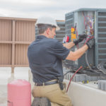 Man performing HVAC maintenance on a rooftop unit