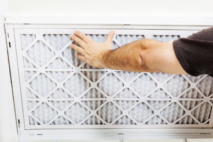 Man performing AC maintenance by replacing the air filter