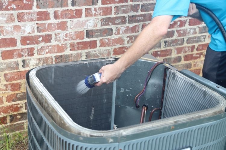 Man cleaning AC condenser coils