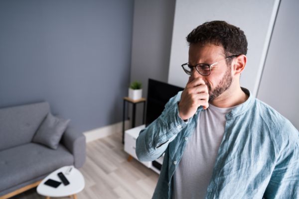 Photo of man holding nose because he needs heating and cooling repair