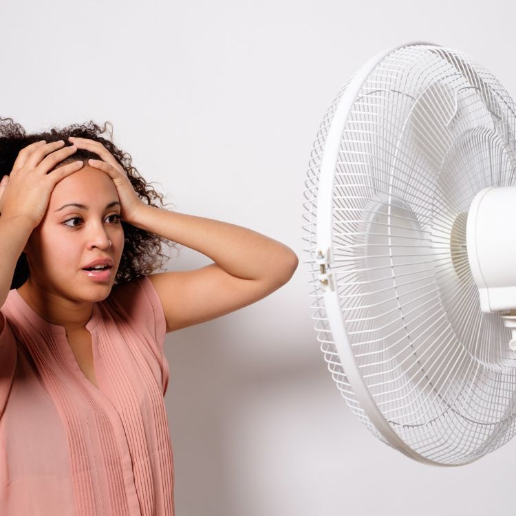 Woman staying cool in front of a fan.