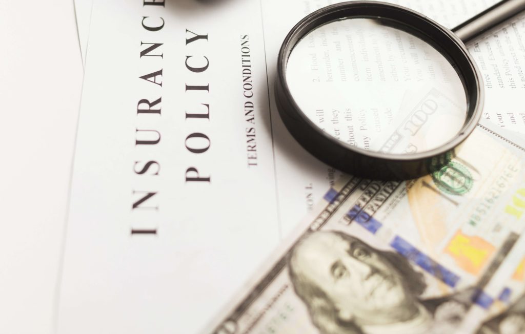 photo of insurance documents with magnifying glass and money