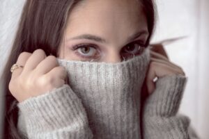 photo of woman hiding face under sweater concerned how to heat home