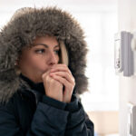 woman in a jacket standing near wall thermometer not turning on heater