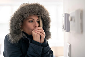 woman in a jacket standing near wall thermometer not turning on heater