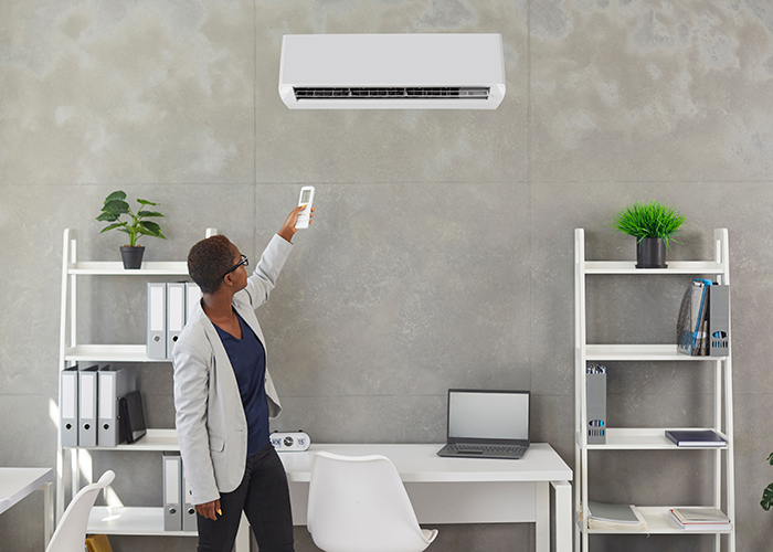 Photo of a woman adjusting a ductless HVAC unit